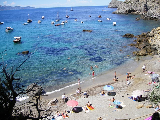 Felsenstrand Cala del Gesso mit kristallklarem Meer und vertäuten Booten.