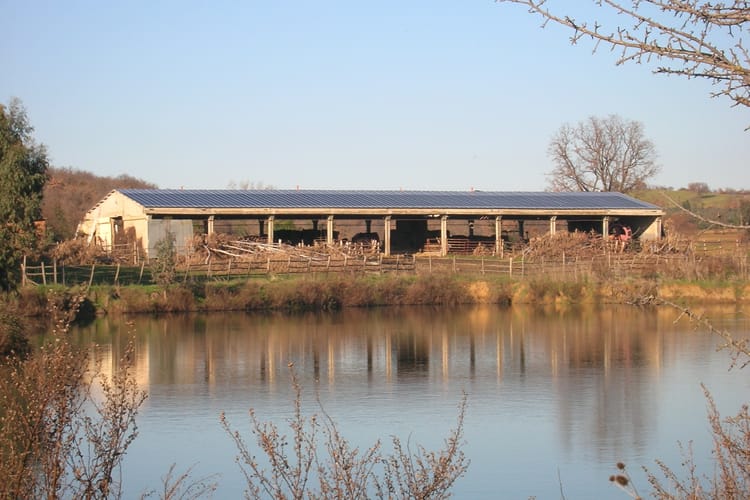 Panele słoneczne na dachu farmy w pobliżu jeziora na wsi.